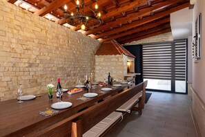 A long wooden dining table set for a meal, with benches and a brick wall in the background. - Villa Peaceful Valley With Heated Pool (Sestanovac)