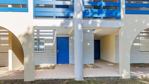 Um edifício de vários andares com porta azul, paredes brancas e uma varanda com grades azuis.