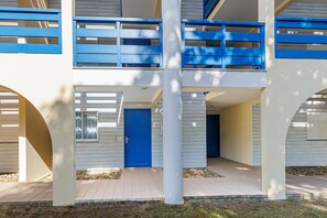 Un edificio de varios pisos con una puerta azul, paredes blancas y un balcón con barandillas azules.