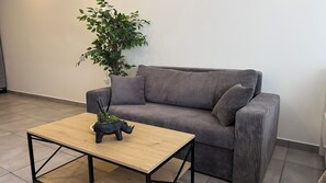 A modern living room with a grey sofa, a wooden coffee table, and a potted plant.