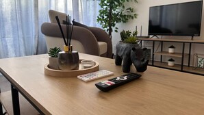 A living room with a wooden table, a TV, a sofa, and a potted plant. - Whole apartment - Studio Noéa (Mâcon)