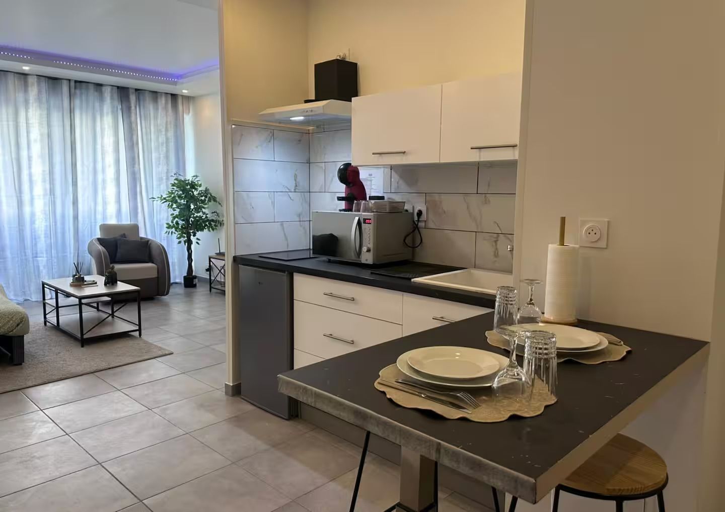 Una cocina moderna con comedor, un sofá y una planta.