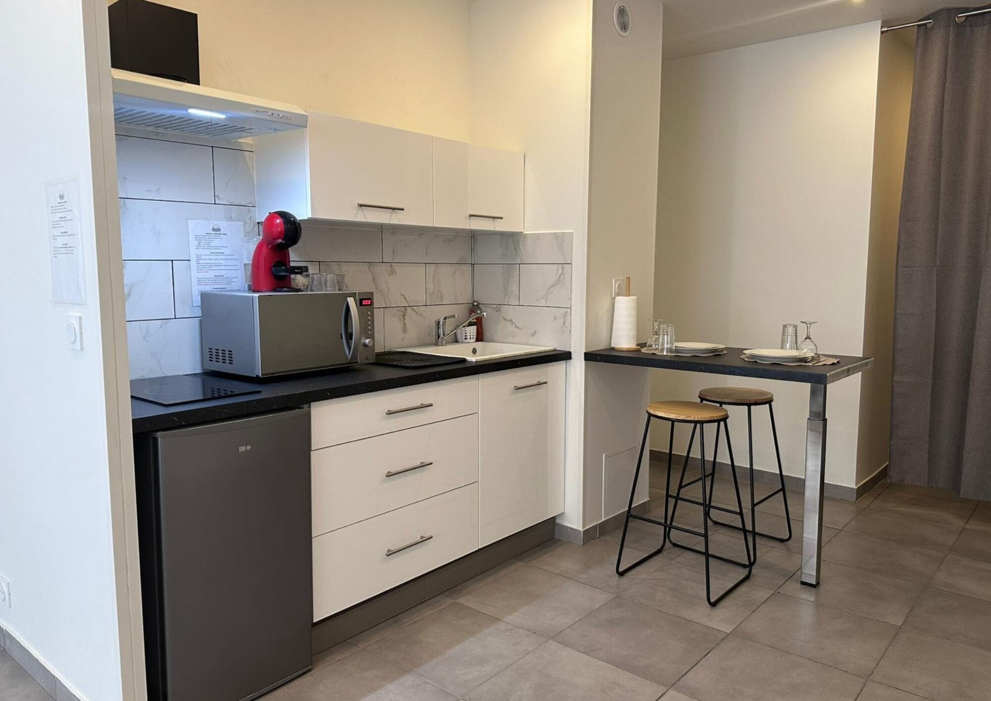 Una cocina moderna equipada con lavavajillas, cafetera, fregadero y un taburete de bar.