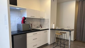 A modern kitchen with a built-in dishwasher, a coffee machine, a sink, and a bar stool. - Whole apartment - Studio Noéa (Mâcon)