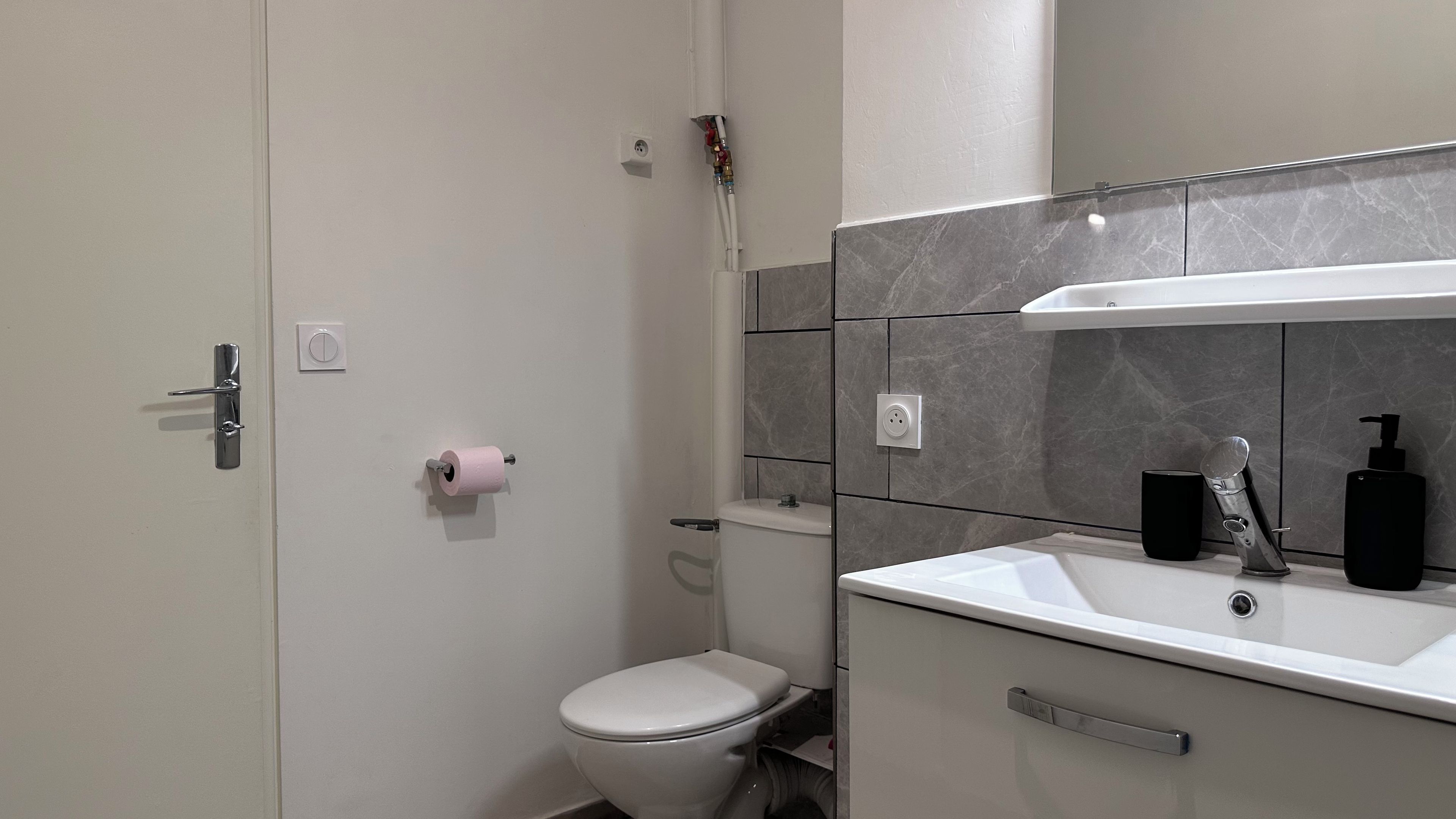 Et moderne badeværelse med toilet, håndvask og bruser.