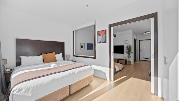 Et moderne hotelværelse med en stor seng, et fladskærms-TV, et natbord og et spejl.