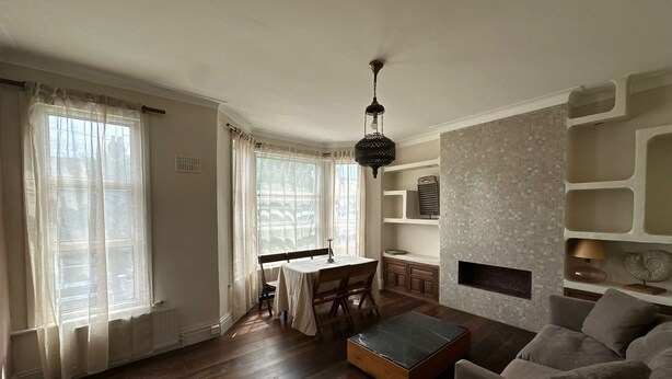 A spacious living room with a wooden floor, a dining area with a table and chairs, a sofa, and a fireplace. - Where English Charm Meets Moroccan Soul - 1 Minute from Kensal Green Station (London)