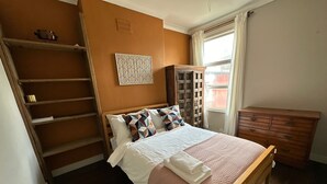 A bedroom with a bed, a wooden dresser, a wardrobe, a ladder, and a window. - Where English Charm Meets Moroccan Soul - 1 Minute from Kensal Green Station (London)