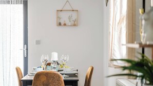 A dining area with a table set for four, a hanging plant, and a window with curtains. - Modern 1-Bed Apartment with Parking near Heathrow (Slough)