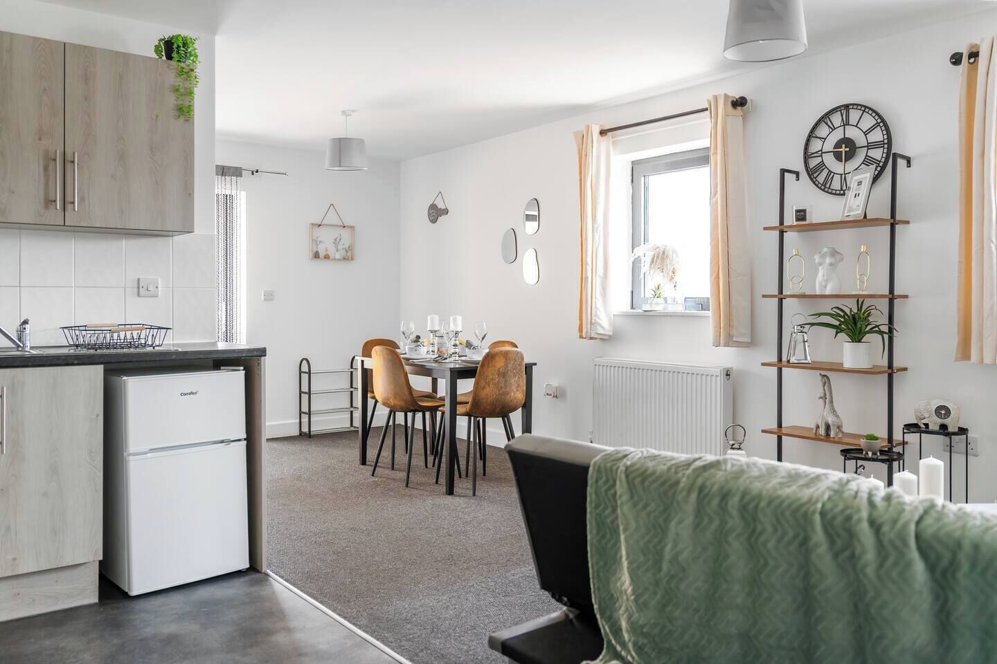 A modern kitchen with a dining area, a radiator, and a clock on the wall.