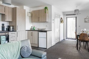 Une cuisine moderne avec des meubles en bois, un lave-vaisselle encastré et un coin repas comprenant une table et des chaises.
