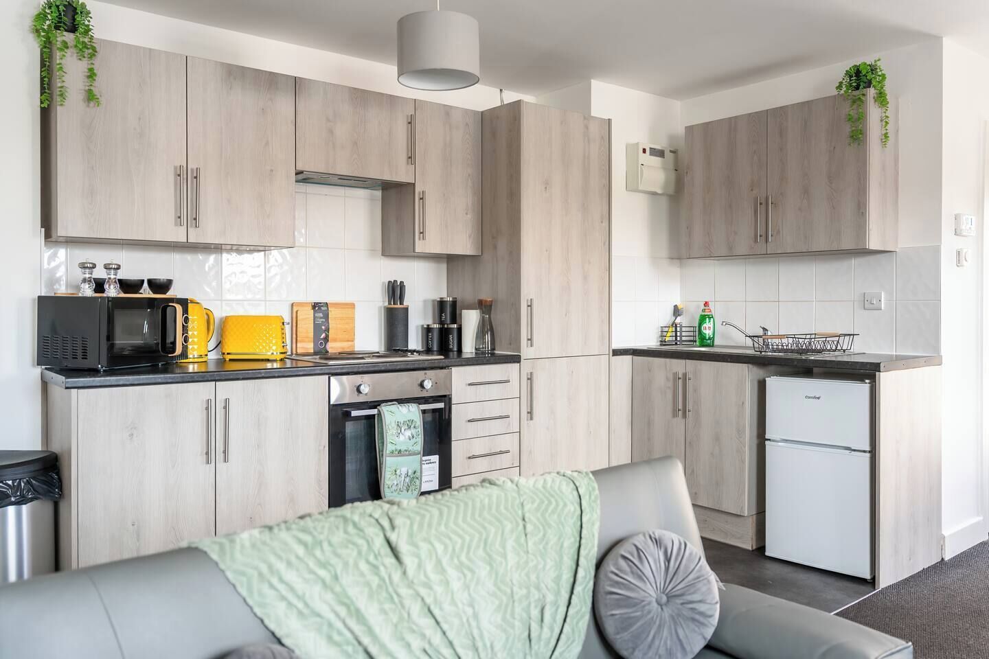 A modern kitchen with wooden cabinets, a microwave, a toaster, and a refrigerator.