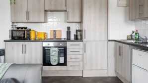 A modern kitchen with light wood cabinets, stainless steel appliances, and a built-in oven. - Modern 1-Bed Apartment with Parking near Heathrow (Slough)