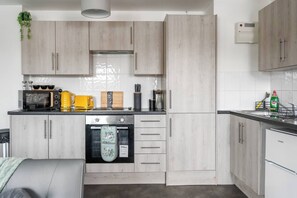 Una cocina moderna con armarios de madera clara, electrodomésticos de acero inoxidable y horno empotrado.