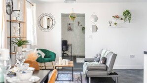 A modern living room with a dining area, a green armchair, a grey sofa, and a coffee table. - Modern 1-Bed Apartment with Parking near Heathrow (Slough)