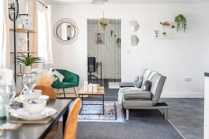 Una sala de estar moderna con comedor, un sillón verde, un sofá gris y una mesa de centro.
