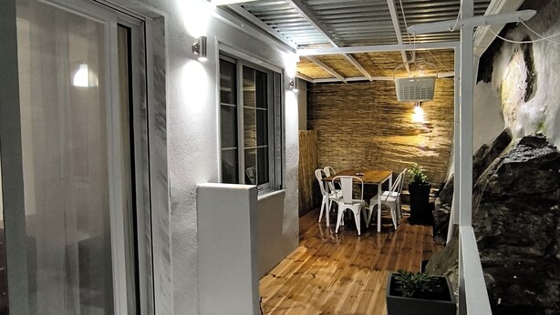 Un intérieur moderne comprenant un coin repas, un mur en pierre et un plafond avec des poutres apparentes.