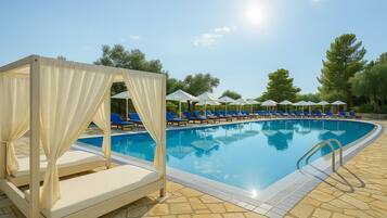 A pool area with blue lounge chairs, a canopy structure, and a stone-tiled deck.
