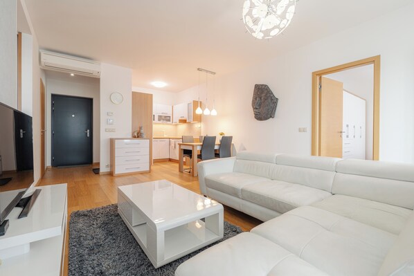En moderne stue med en hvid sofa, et glasbord og et spiseområde med et træbord og stole.