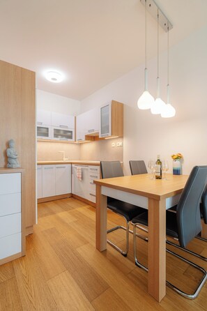 Et moderne køkken med træskabe, et spisebord med stole og en hængende lampe.