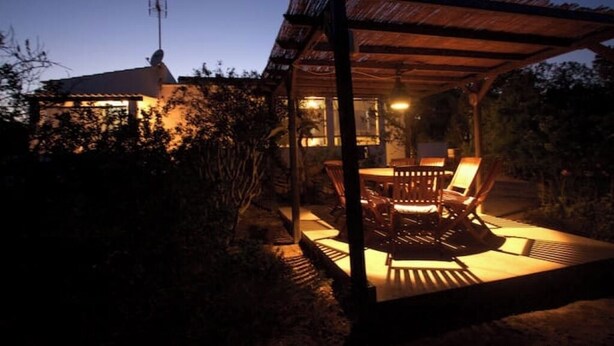 A covered outdoor seating area with a table and chairs, surrounded by vegetation. - Rural House Ca Ses Llussianes - ET/0641 (Sant Francesc de Formentera)