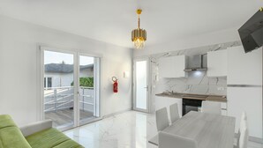 A modern kitchen with a dining area, a sliding glass door to the outside, and a ceiling-mounted light fixture. - Apartment 'Teresa' with Shared Pool, Private Terrace and Air Conditioning (Bibione)