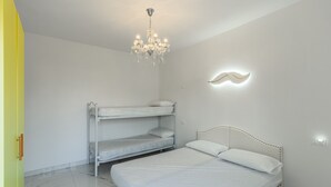 A bedroom with a bunk bed, a single bed, a chandelier, and a wall-mounted light fixture. - Apartment 'Teresa' with Shared Pool, Private Terrace and Air Conditioning (Bibione)