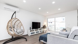En moderne stue med fjernsyn, sofa og en fletstol.