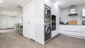 Et moderne køkken med indbyggede apparater, et spiseområde med stole og trægulv.
