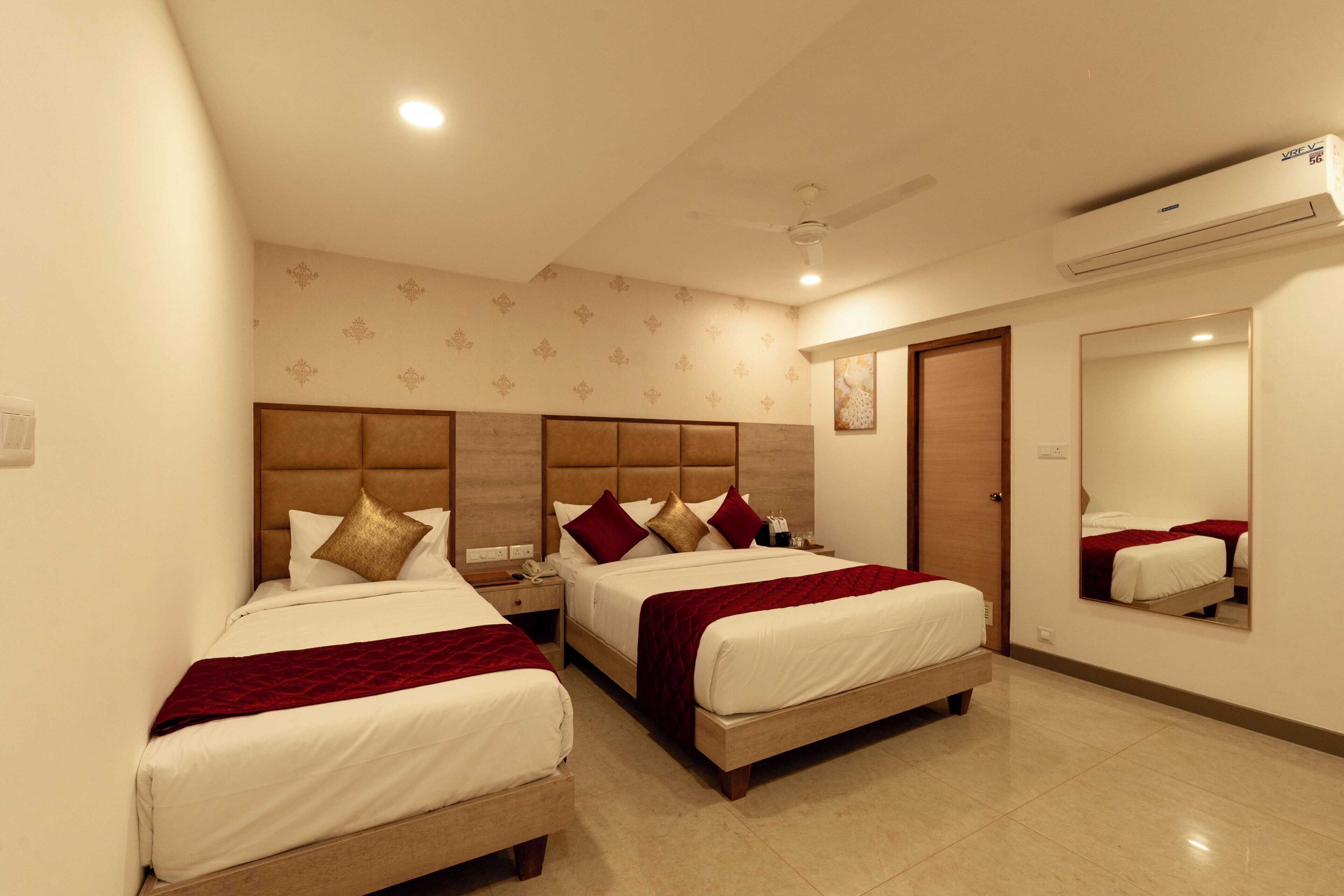 A hotel room with two beds, a large mirror, and an air conditioning unit.