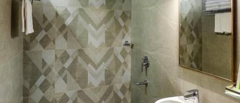 Un baño con pared de diseño en zigzag, ducha, lavamanos y espejo.