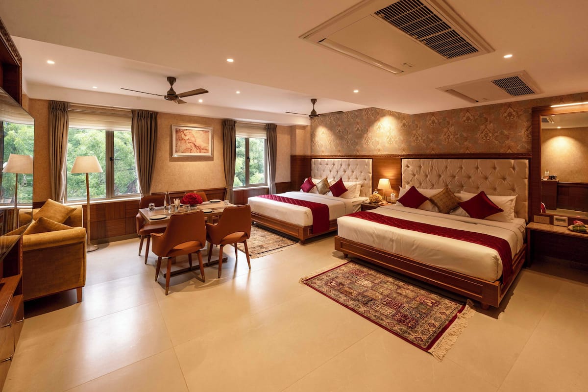 A hotel room with two beds, a dining area, and a sitting area.
