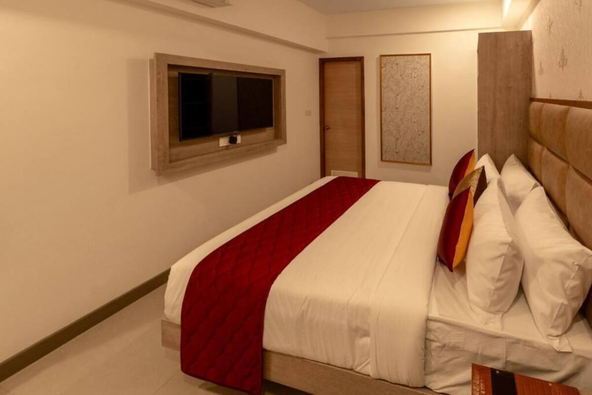A bedroom with a bed, a window, a door, and a wall-mounted artwork.