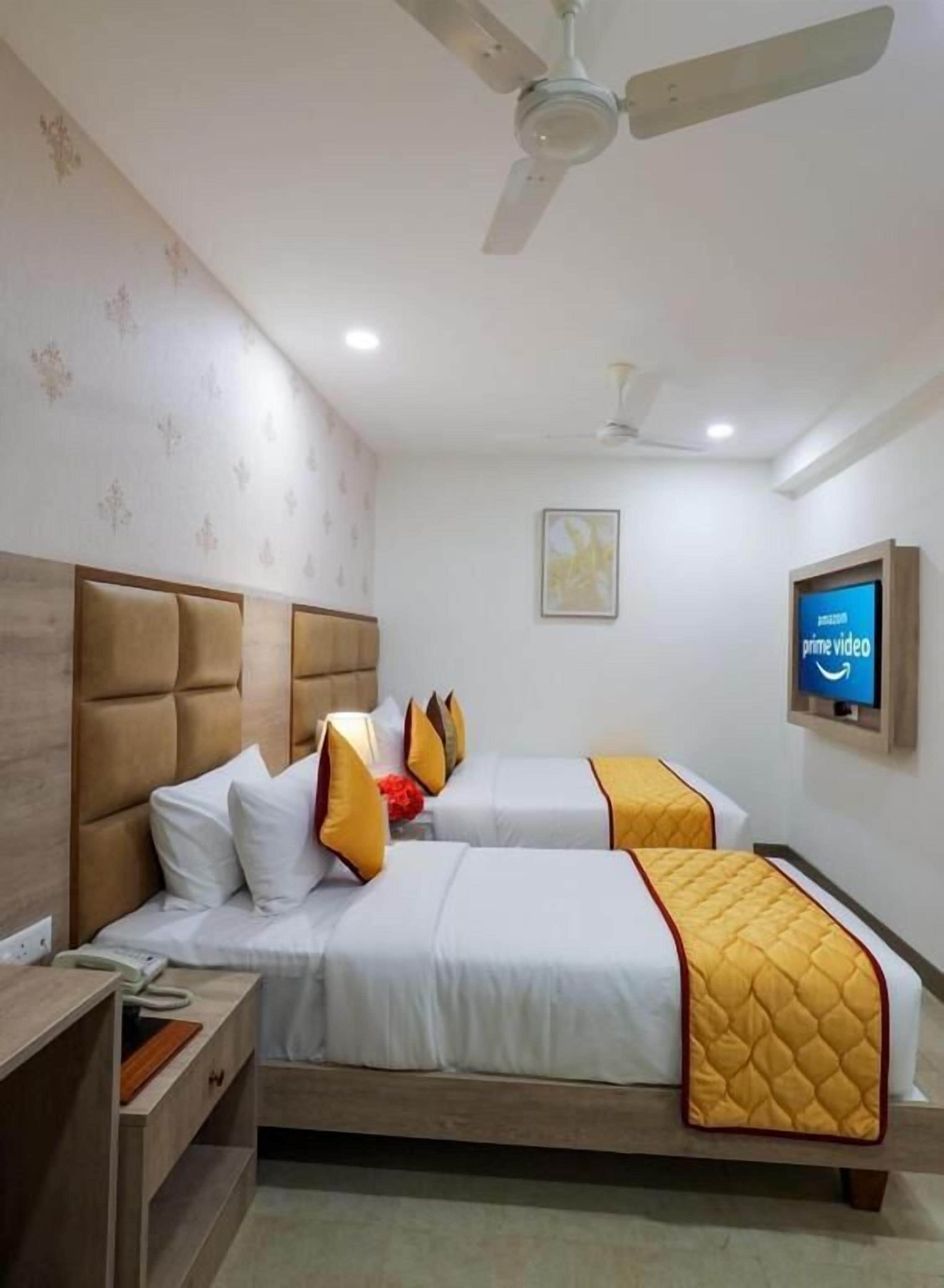 Une chambre d’hôtel avec deux lits, un ventilateur de plafond, une télévision et une table de chevet.