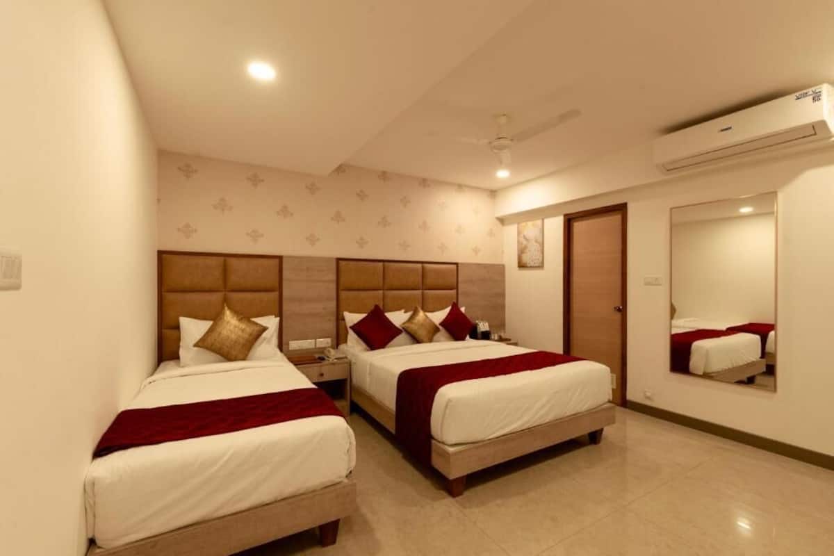 A hotel room with two beds, a large mirror, and an air conditioning unit.