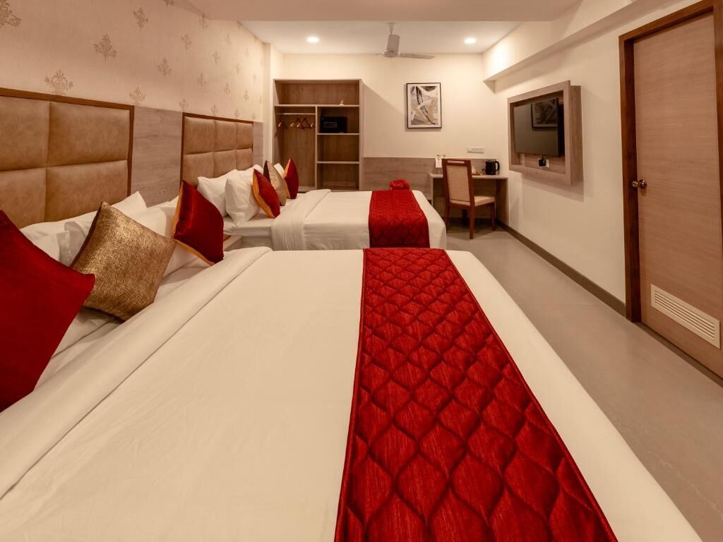 A hotel room with two beds, a desk, a chair, a television, and a wardrobe.