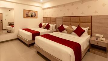 A hotel room with two beds, a bedside table with a phone, and a mirror.
