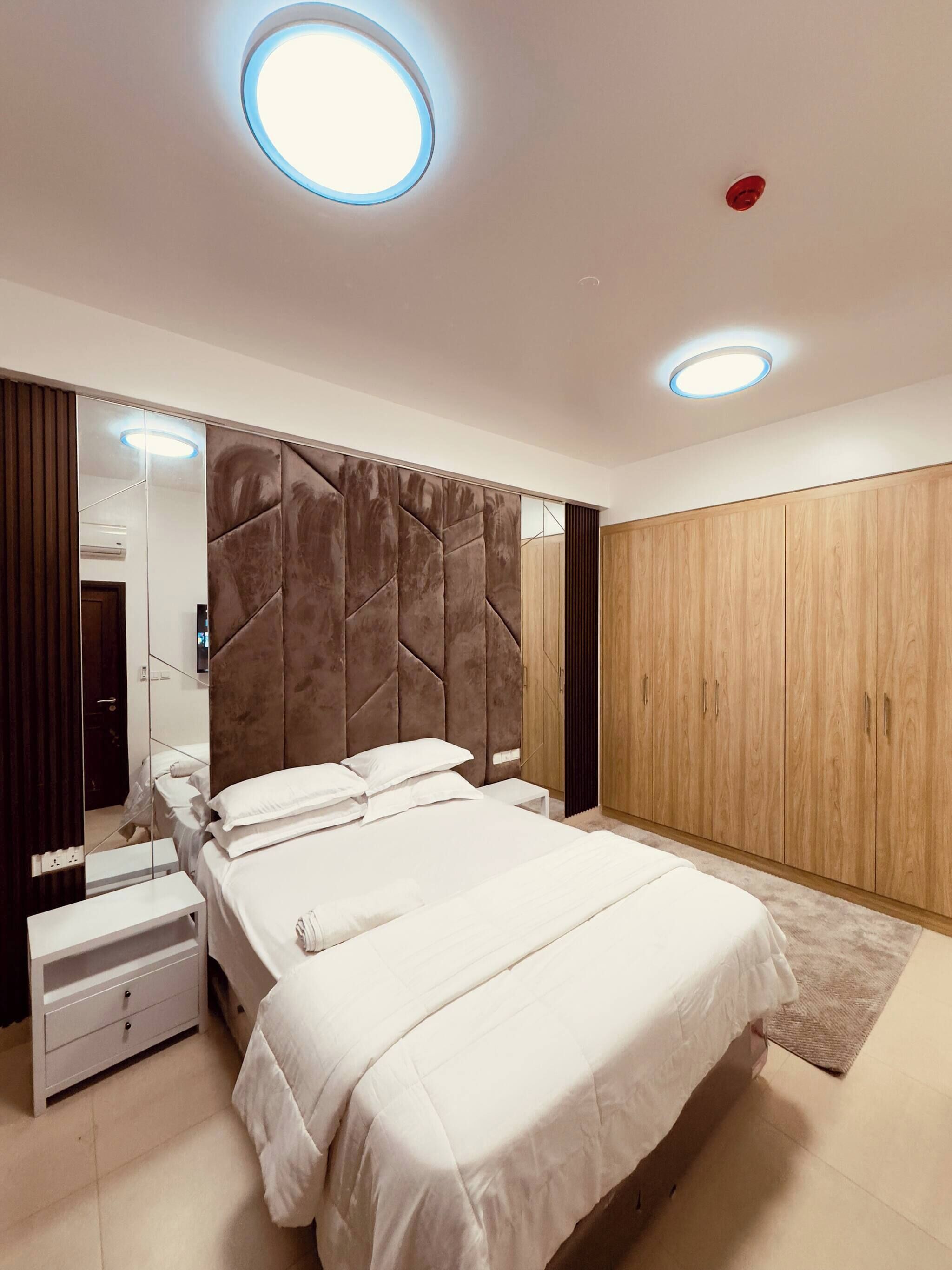 Ein modernes Schlafzimmer mit einem großen Bett, einem Kleiderschrank und einem Spiegel.