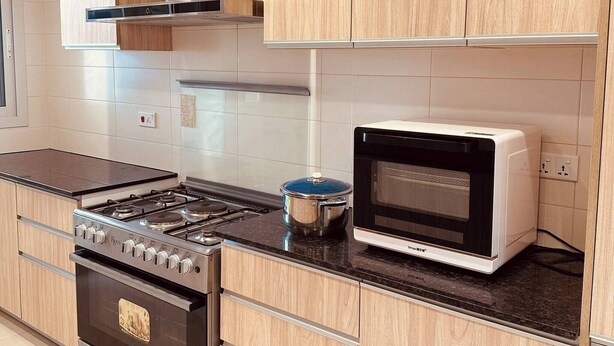 Una cocina moderna con armarios de madera, estufa a gas, horno y microondas.