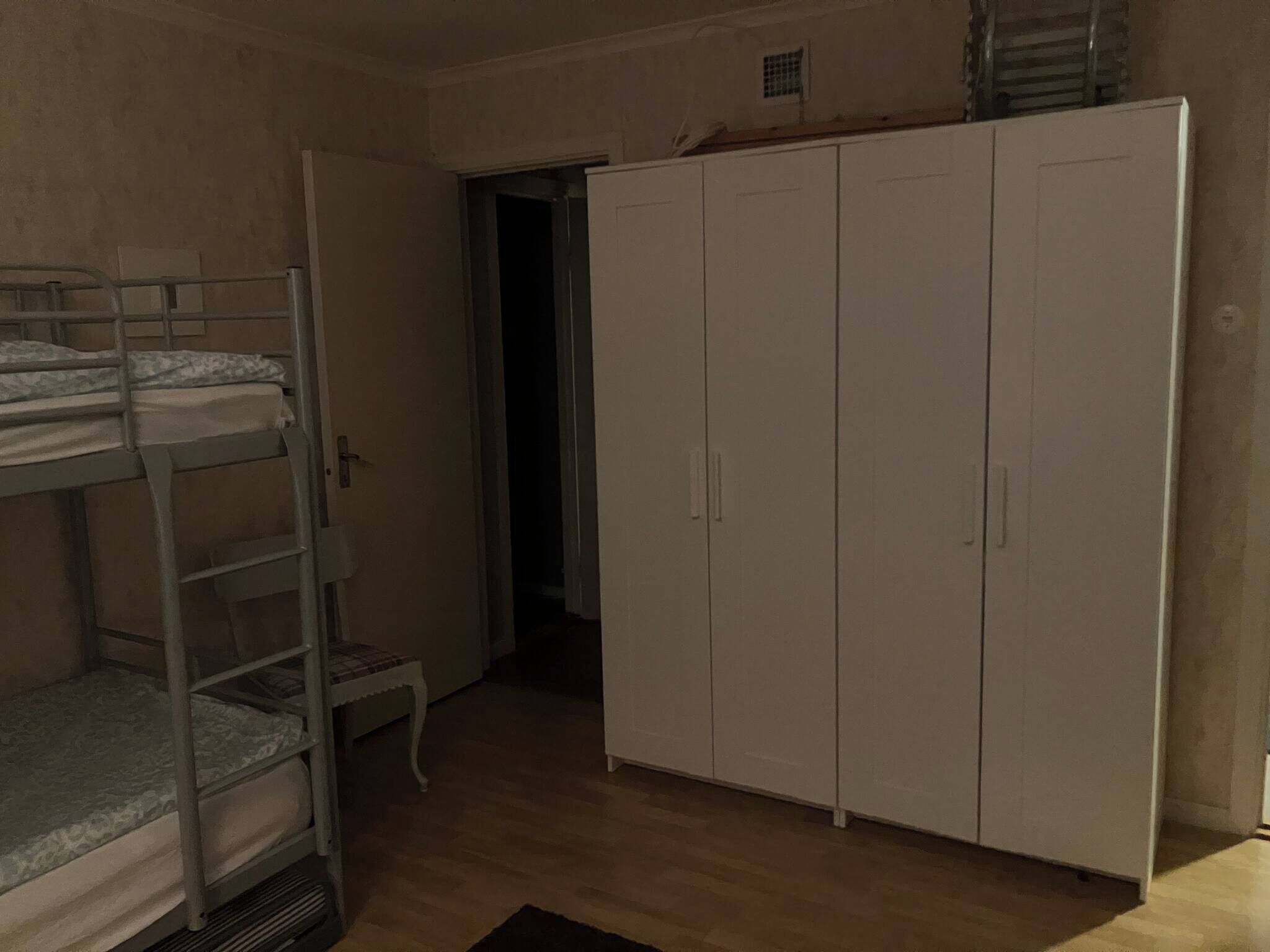 Um quarto com beliches, um guarda-roupa e uma pequena mesa.
