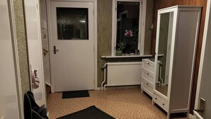 A small, compact room with a white door, a radiator, a mirror, and a white dresser. - Large Family Housing (Mariannelund)