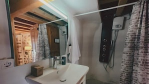 Un baño con un lavamanos blanco, un espejo, una toalla colgada en la pared y una zona de ducha con cortina.