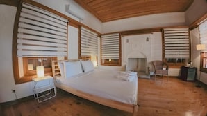 Un dormitorio con una cama de madera, una mesita de noche, una silla y una chimenea.