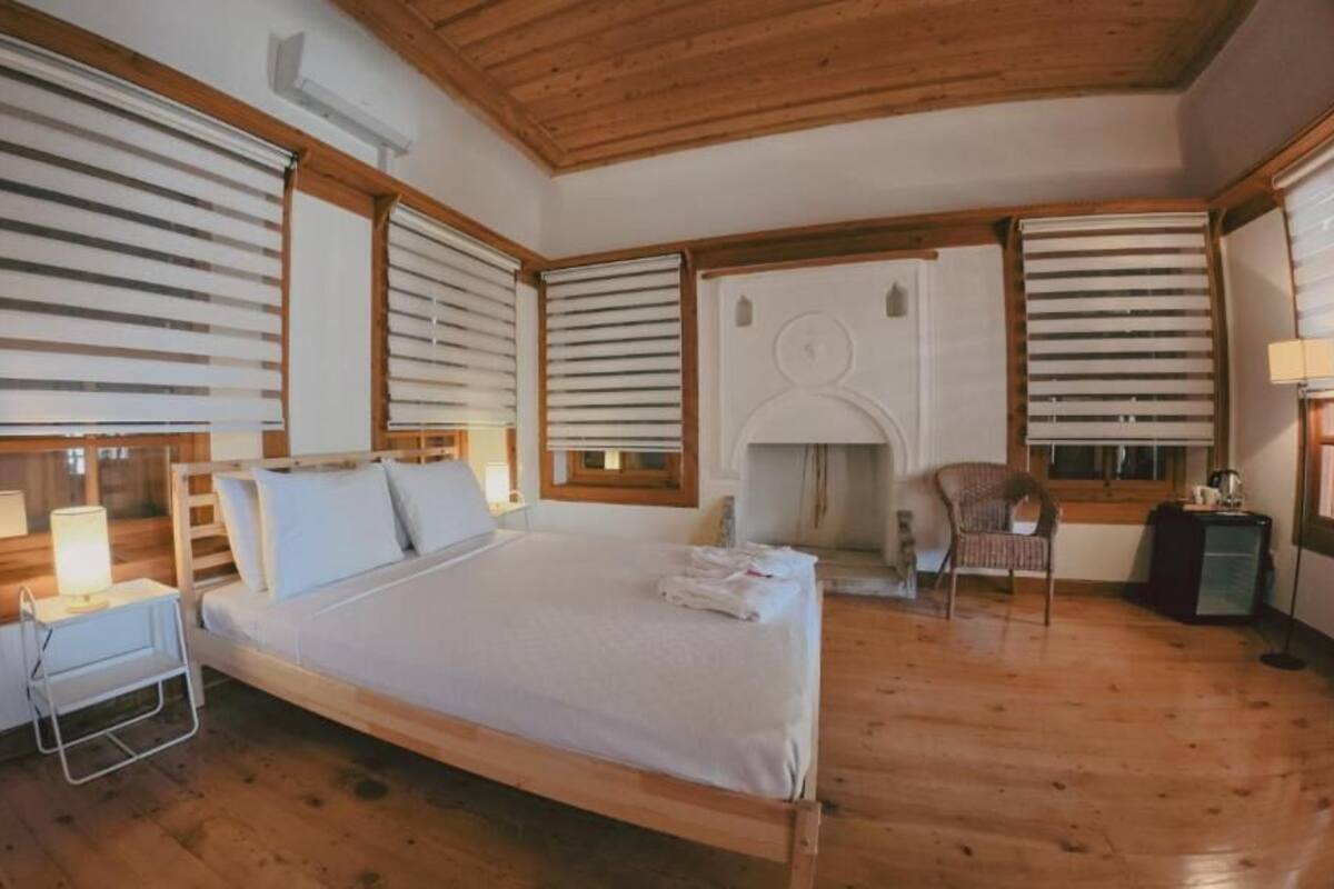 A bedroom with a wooden bed, a nightstand, a chair, and a fireplace.