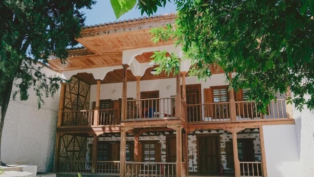 Un edificio tradicional con un balcón de madera y fachada de piedra.