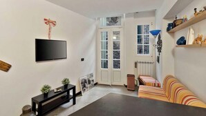 Ein Wohnzimmer mit Flachbildfernseher, einer Couch, einem Couchtisch und einem Kamin.