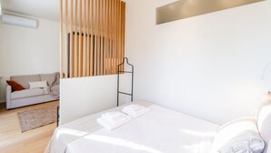 Une chambre moderne avec un lit, une cloison en lattes de bois, un canapé et une petite table.