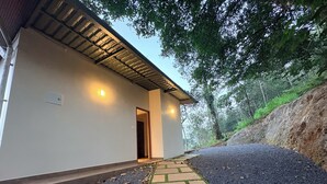 Un bâtiment moderne doté d’un toit en pente, d’un chemin de pierre menant à l’entrée et entouré d’un paysage naturel.