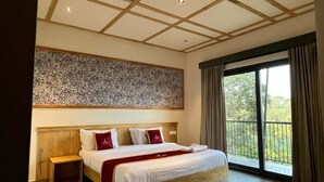 Une chambre spacieuse avec un grand lit, une table de chevet, un mur décoratif et un balcon agrémenté de rideaux.