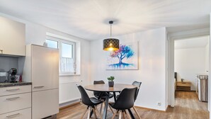 Et moderne køkken med spiseplads, et stort vindue og et træmaleri.